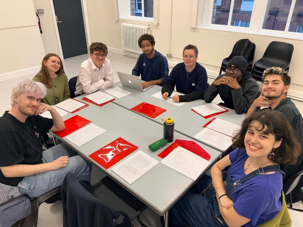 The cast and crew of Bolivian affairs sat around a table covered in scripts.