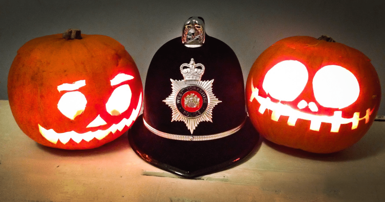 An image of tow lit up pumpkins either side of a police hat