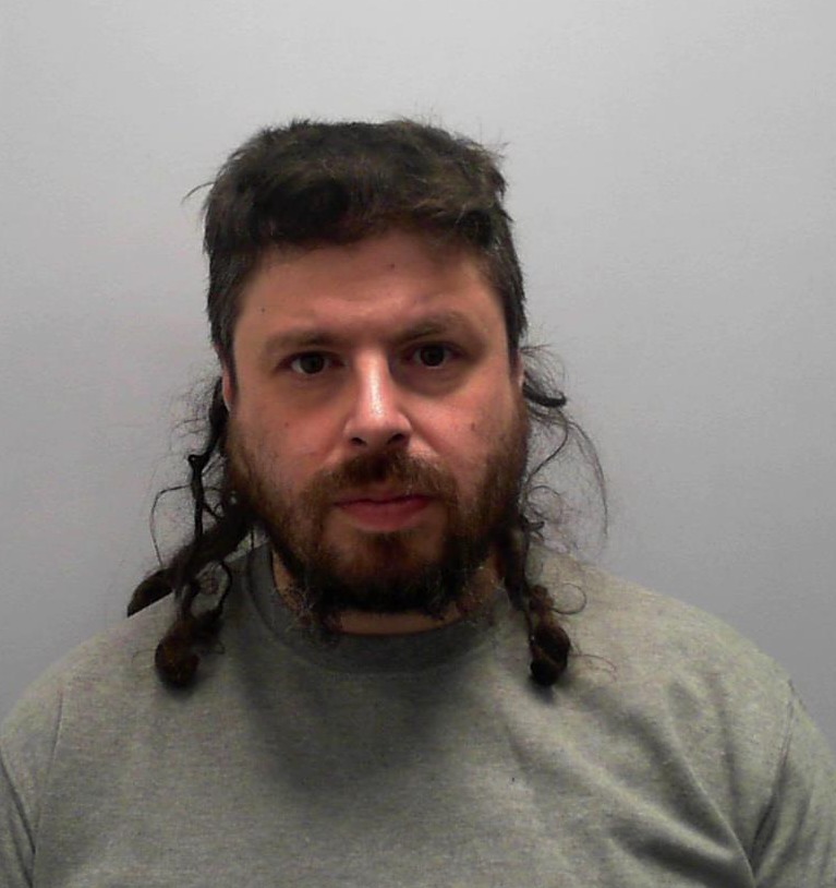 Headshot of a white male with long, straggly brown hair.