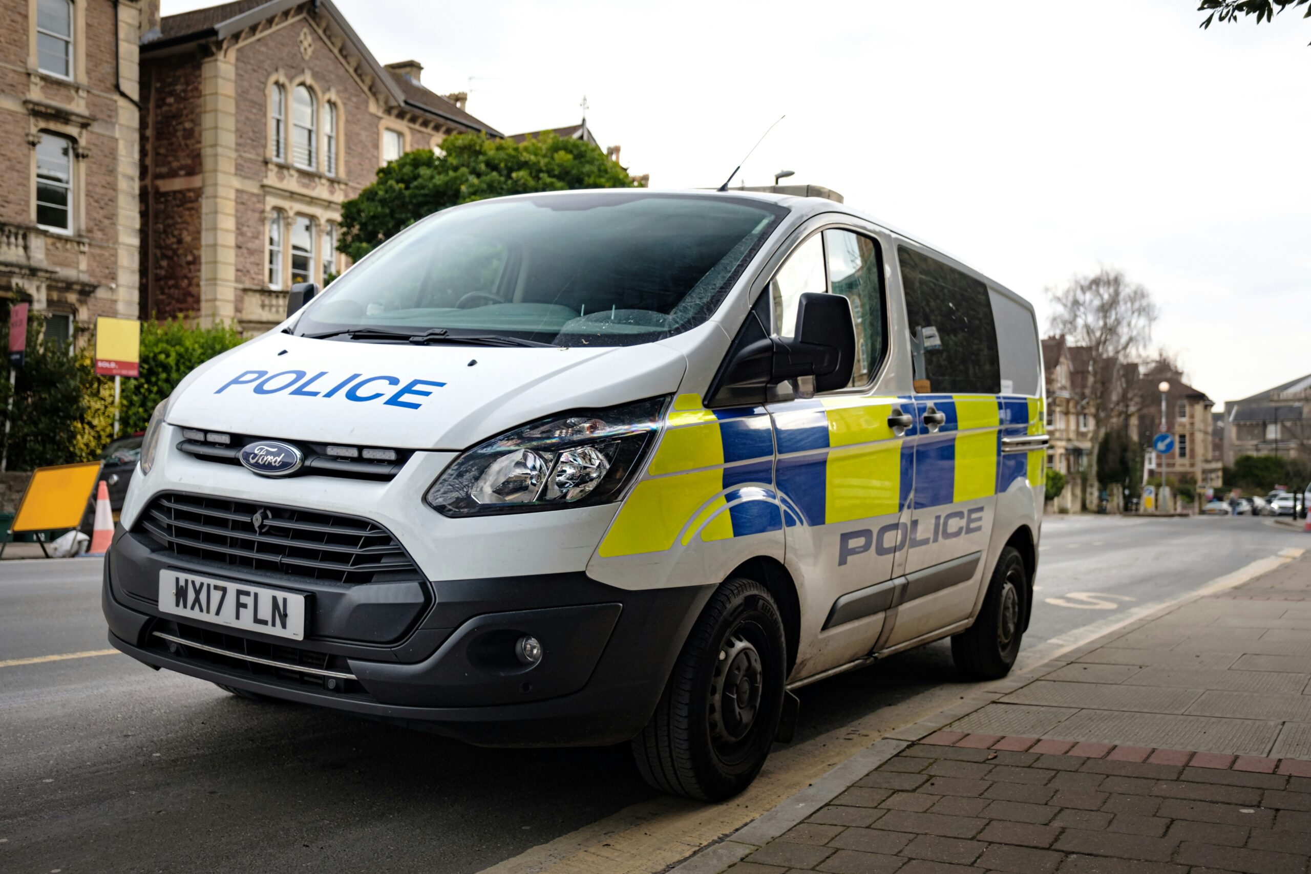 A UK police van is parked on the side of a residential road.