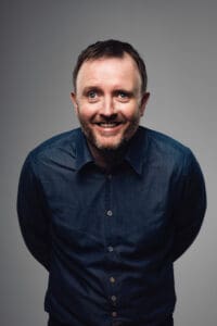 Portrait photo of a man facing and leaning towards the camera