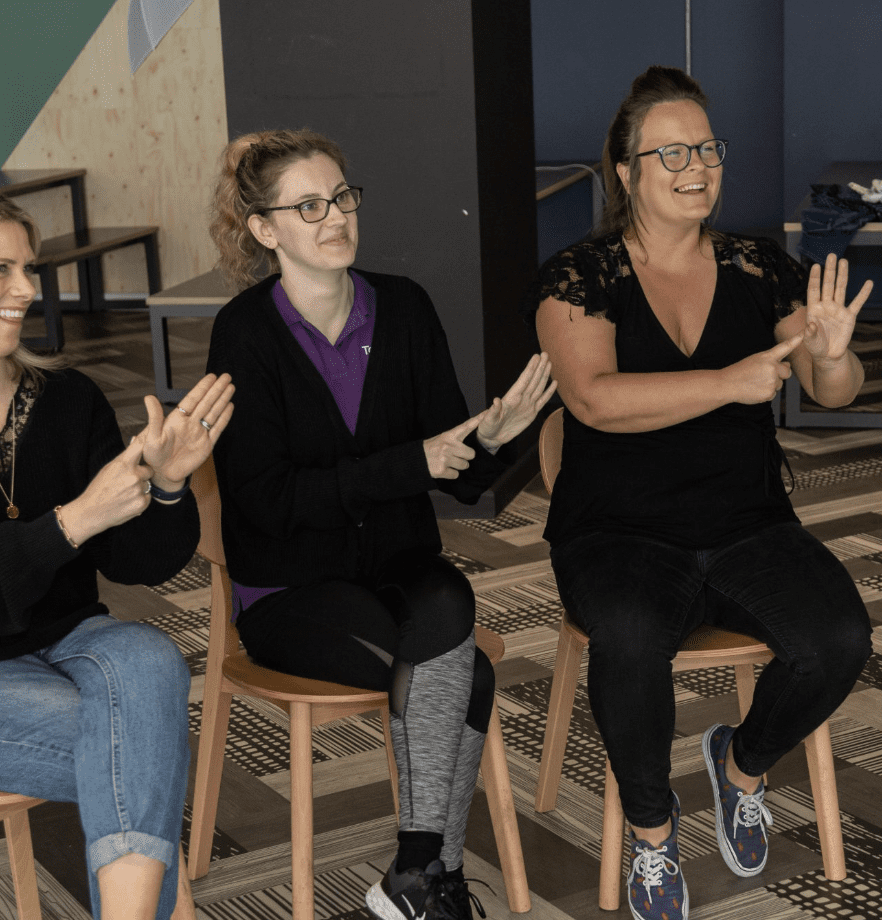 Group of seated women wearing black clothing and learning BSL