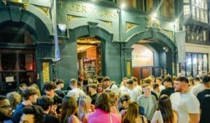 Clubbers waiting in a crowd outside the blue and gold front of the Tiger works doors. Lights shine over the gold tigers
