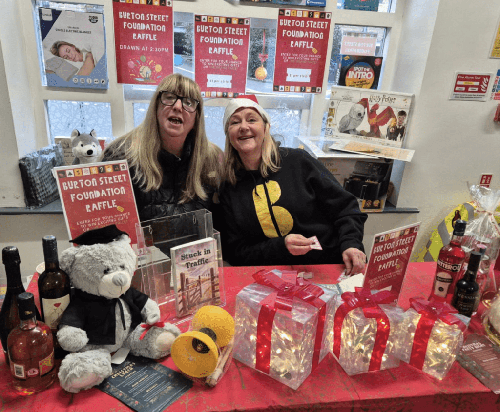 two women sitting at table with christmas decorations and raffle prizes