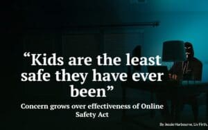 Man at glowing desk wearing a mask and staring into camera