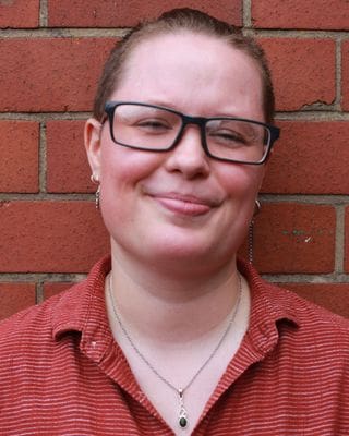 Person with glasses and red shit smiling for photo