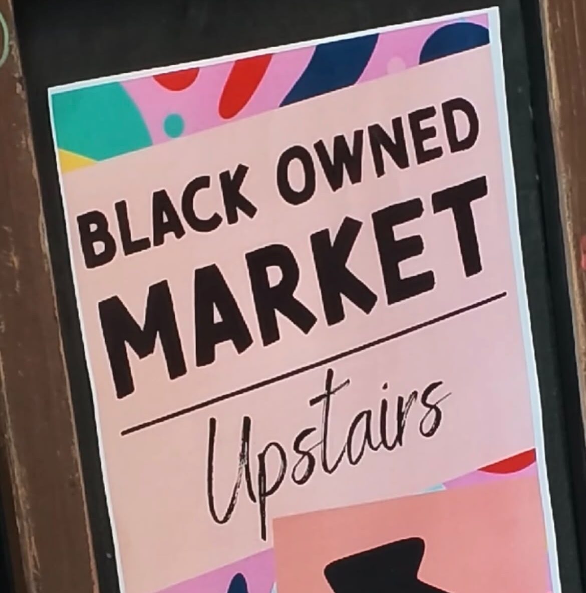 1441eac7-492c-4a67-9d98-1584816fe040 (1) A colourful pastel sign with the words ''BLACK OWNED MARKET Upstairs'.