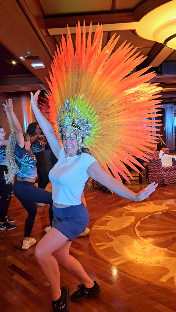 Jenny smiling at the camera with a big Brazilian headdress on her head