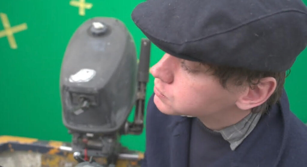 man on fake boat in front of green screen