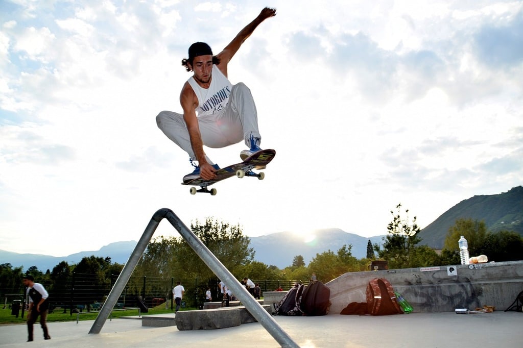 A man on a skateboard jumping over a metal railing / A man riding a skateboard down a metal rail / Public domain photo of a park, nature.